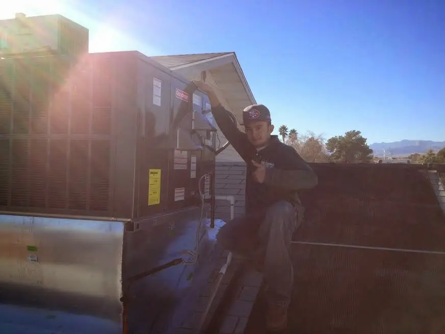 HVAC technician performing AC Tune-Up on a rooftop unit in Urbana